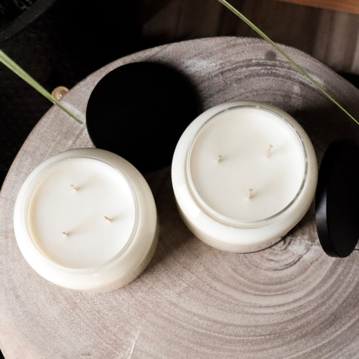 Two white candles on a wooden surface with a dark background
